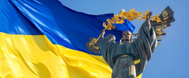 Monument of independence of ukraine in front of the ukrainian flag. the monument is located in the center of kiev on independence square. russian war in ukraine. stop war.